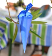 Kleine blaue Zuckertüte hängt an einem Zweig als Dekoration zum Schulanfang