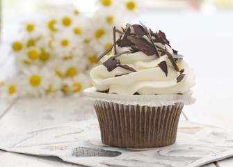 Muffin. Cupcake with chocolate and daisy flower.