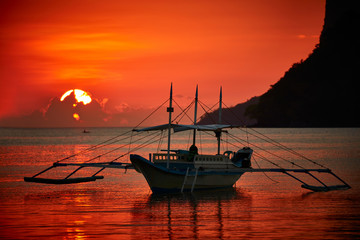 Traditional filippino boat at El Nido bay in sunset lights.  - obrazy, fototapety, plakaty