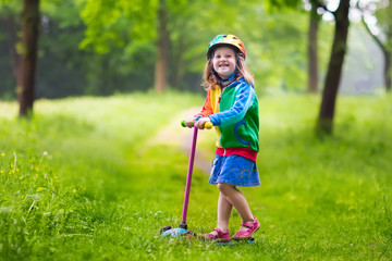 Little girl riding a colorful scooter