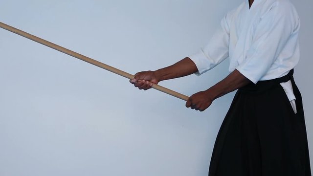 Martial arts Master in black hakama practice martial arts with wooden jo stick on white background