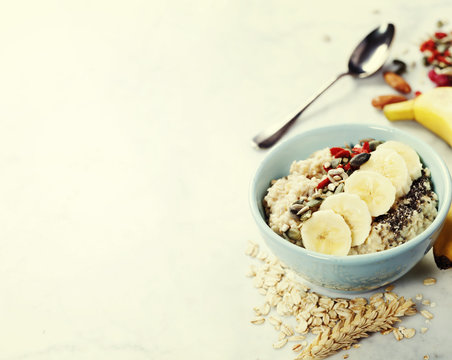 Healthy breakfast. Home made oatmeal porridge, goji berries, pumpkin and chia seeds  in a ceramic bowl on white background.