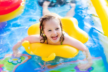 Little girl playing in inflatable garden swimming pool