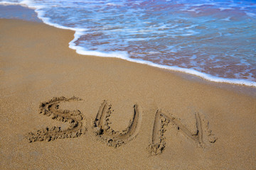 Fototapeta na wymiar Sun spell written work in sand of a beach