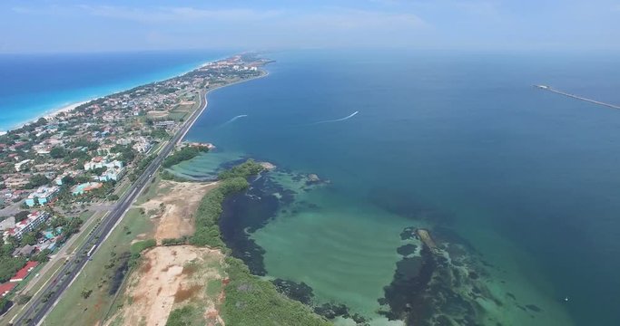 VARADERO, CUBA - MAY 20, 2016: Drone flies over tropical island on a clear day. Calm Atlantic Ocean and the bay. Flying over the city. On the road going car, close to the shore. Height of 500 meters