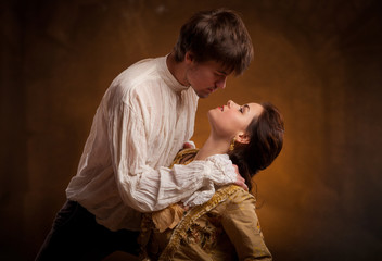 Portrait of young couple in love posing at studio dressed in classic clothes