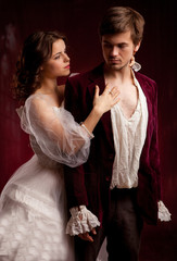 Beautiful man and woman dressed in medieval clothing stand in a room of the old abandoned castle.