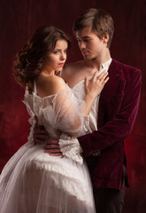 Beautiful man and woman dressed in medieval clothing stand in a room of the old abandoned castle.