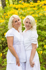 Fototapeta premium Beautiful cute blonde girl standing near flowers