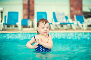 Naklejka premium Happy child in swimming pool, beautiful girl swims