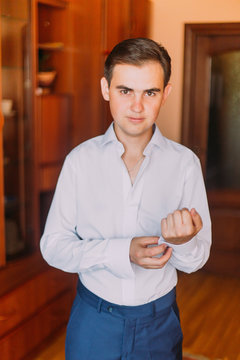 Young handsome man dressing up in hotel room before the formal event