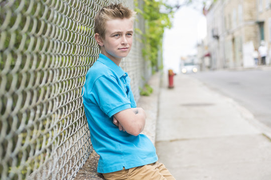 young teen boy looking out of a fence