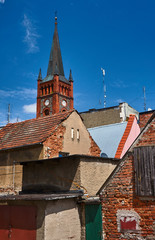 Obraz premium Roofs of houses and a church tower with a clock in Niemcza.