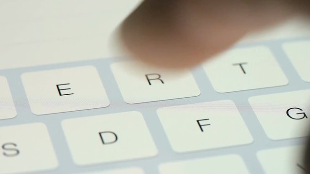 Finger touching virtual keys form a digital keyboard of a touchscreen iPad tablet device.