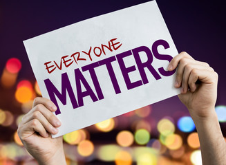 Everyone Matters placard with night lights on background