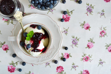 Vanilla ice cream with blueberry jam in a cup with space for tex