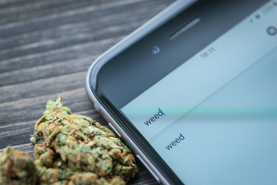Phone and weed on a rustic wooden board
