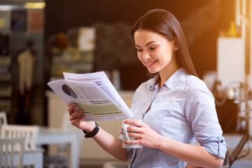 Positive woman reading newspaper