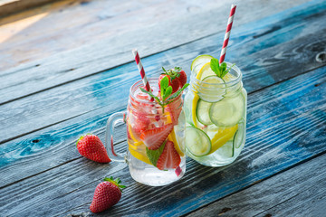 Jugs with lemon, lime and strawberry infused water on a rustic wooden surface
