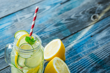 Jug with lemon and lime infused water on a rustic wooden surface