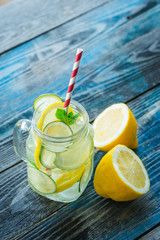 Jug with lemon and lime infused water on a rustic wooden surface