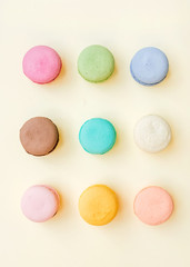 Sweet colorful French macaroon biscuits on pastel yellow background