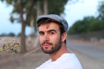 Farmer is looking his grain field with a straw of wheat ears in his mouth