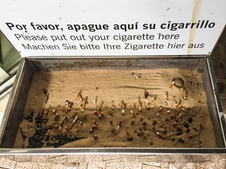 Big ashtray with cigarette fags on airport.