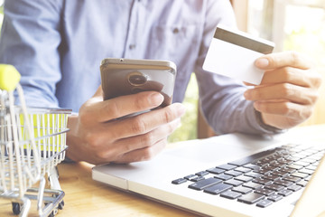 Man using laptop and mobile phone to online shopping and pay by credit card. Vintage tone, Retro filter effect, Soft focus, Low light.(selective focus)