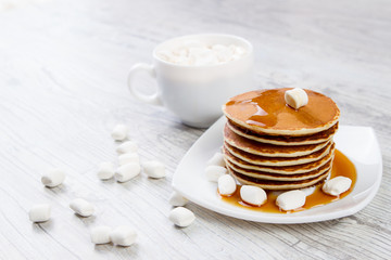 Tasty pancake on a white plate, wooden background, maple syrup