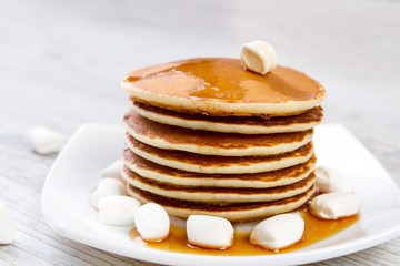 Tasty pancake on a white plate, wooden background, maple syrup