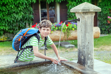 young tourist is drinking water from stone spring