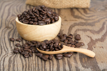 Coffee beans in  wood spoon and on old wood table