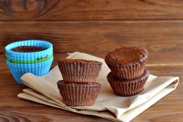 Perfectly chocolate cupcakes on paper and wooden table. Baking cakes at home. Soft sweet homemade muffins using silicone bakeware