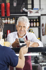 Fototapeta na wymiar Salesman Accepting Payment From Customer Through Credit Card