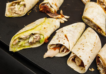 Selection of tasty wraps lying on black surface, as seen from above