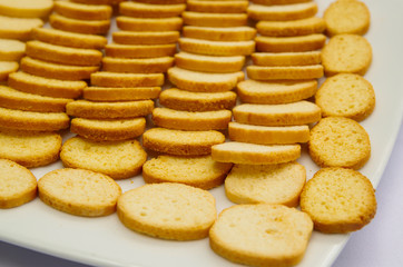 Thin crunchy toasted baguette slices stacked up on white plate