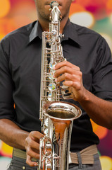 Obraz premium Closeup hands of man wearing dark shirt and playing saxophone