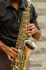 Obraz premium Closeup hands of man wearing dark shirt and playing saxophone