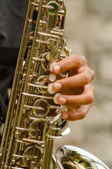 Closeup hands of man wearing dark shirt and playing saxophone