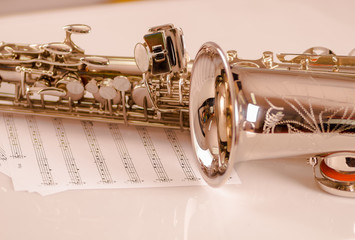 Obraz na płótnie Canvas Closeup partly view of shiny saxophone lying on musical notes paper