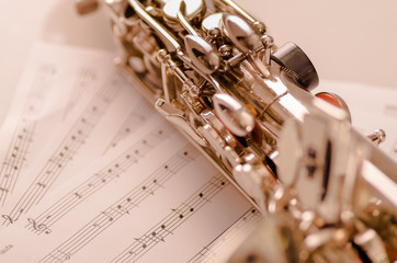 Obraz premium Closeup partly view of shiny saxophone lying on musical notes paper