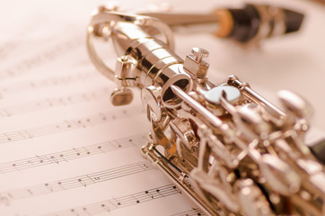 Fototapeta premium Closeup partly view of shiny saxophone lying on musical notes paper