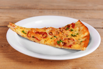 Tasty slice of pizza on plate on wooden table