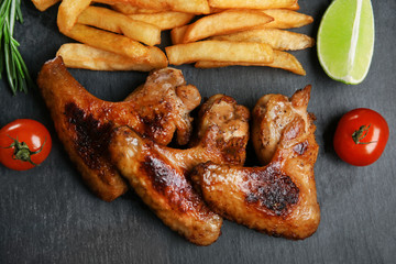 Baked chicken wings with French fries on slate plate