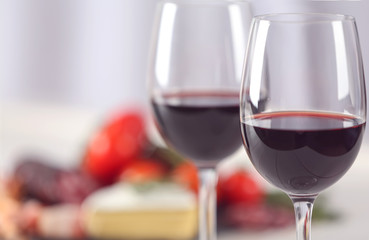 Glasses of red wine with food on blurred background