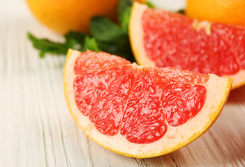 Fototapeta na wymiar Sliced grapefruits with mint on wooden background, close up