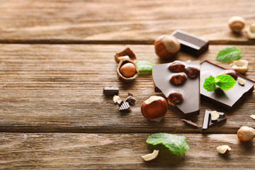 Chopped chocolate bar  with mint and hazelnuts on wooden table.