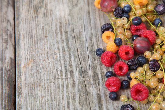 Various ripe berries on old wooden table