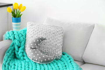 Stylish pillows with turquoise plaid on white couch